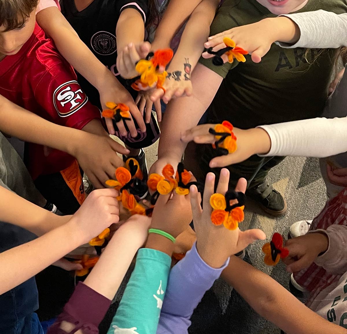 Students with pipe cleaner monarch rings on hands