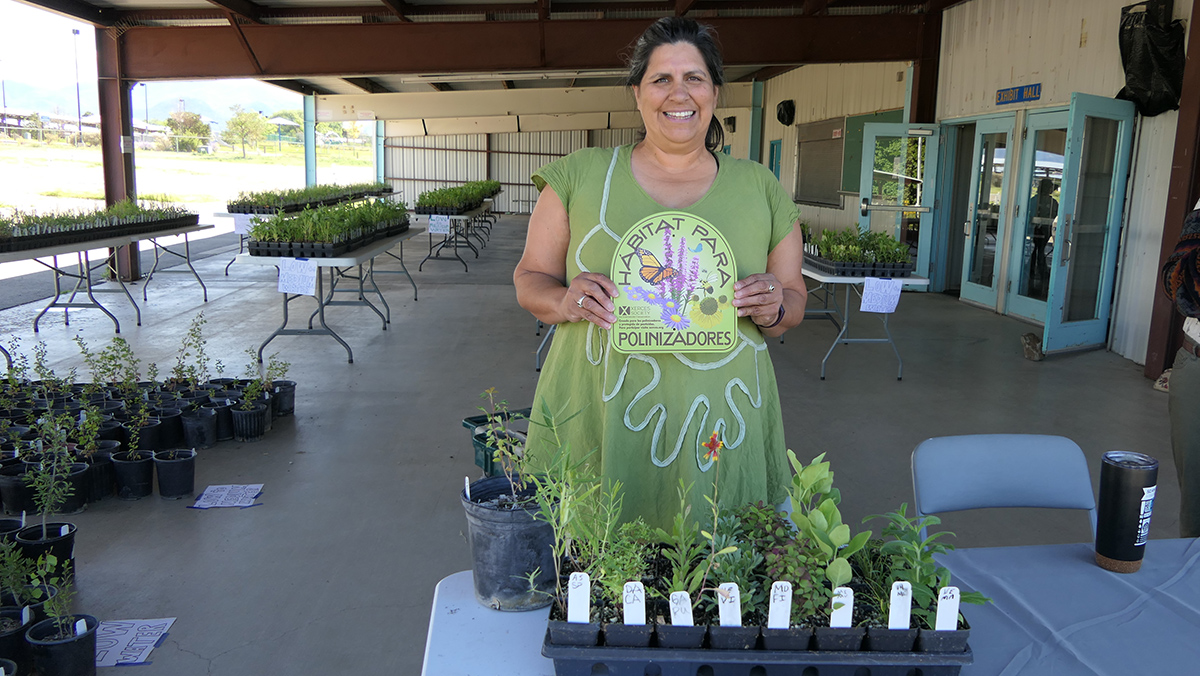 Participant poses with new plants and pollinator habitat sign
