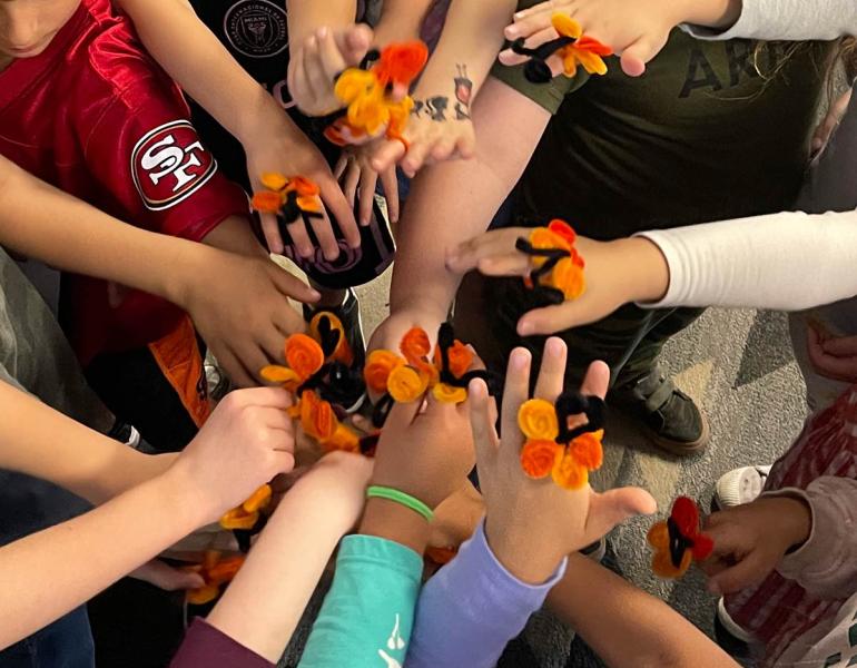 Group of students with pipe cleaner monarch rings on hands