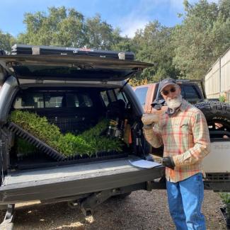 Man poses with California Habitat Kit plants in truck during pickup. Credit: Angela Laws.