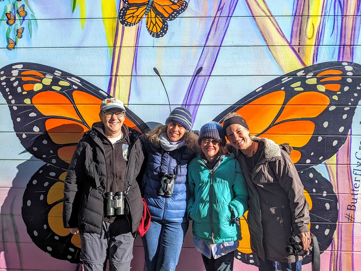 Grupo de personas en frente de un mural de mariposas