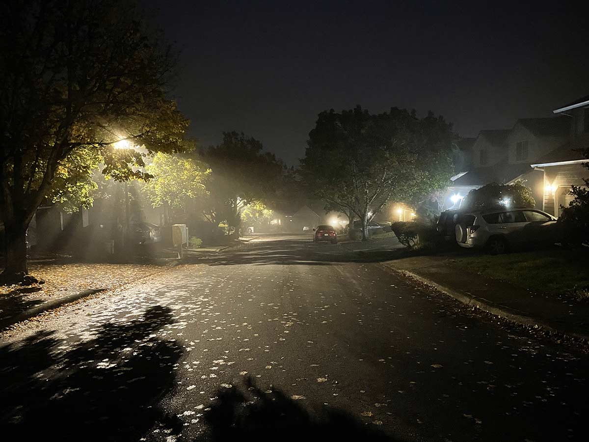 A suburban street at night, showing many overly bright lights.