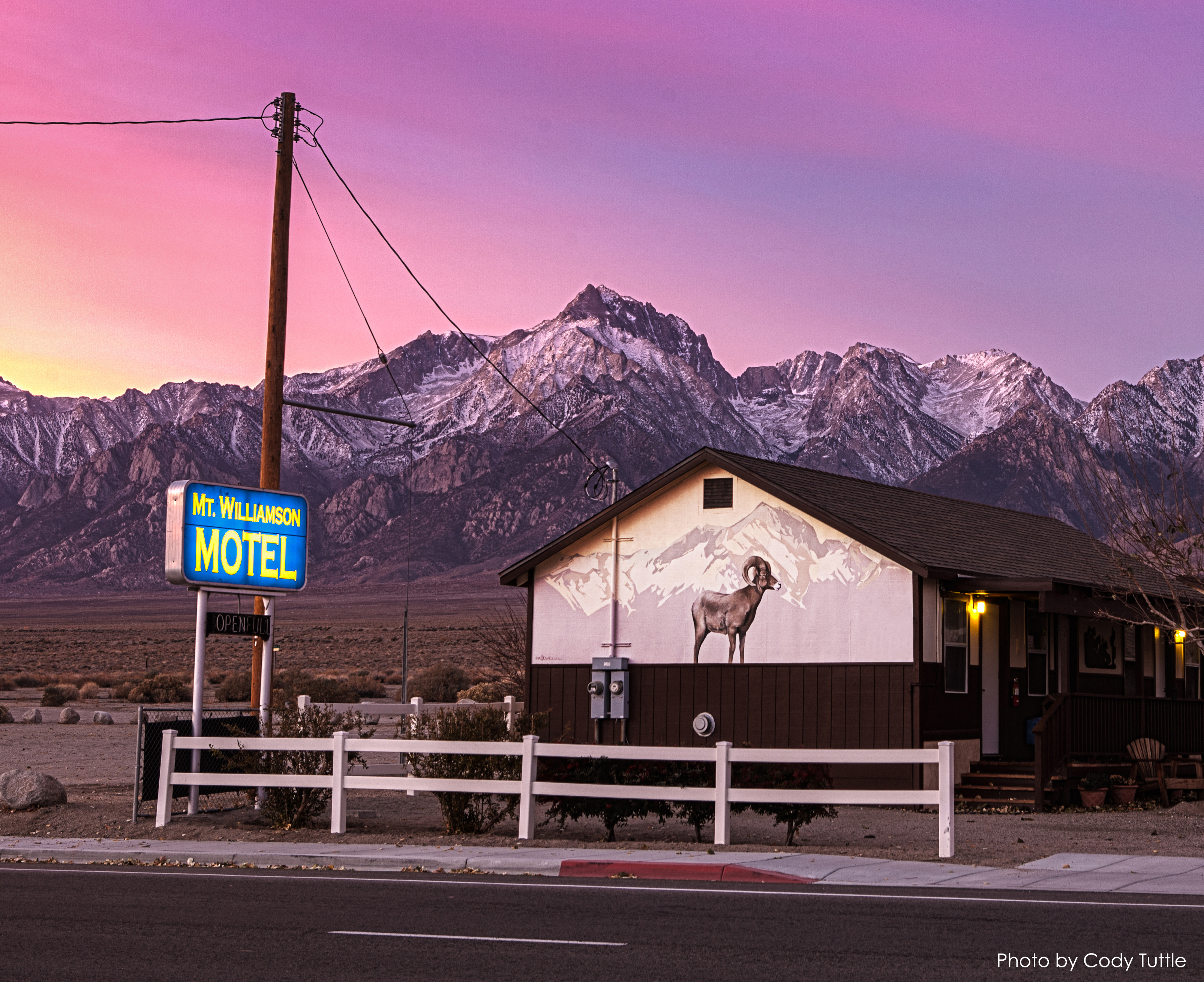 Mural of a bighorn sheep on the end of a motel building. The snow-capped mountains of California's Sierra Nevada rise in the background.
