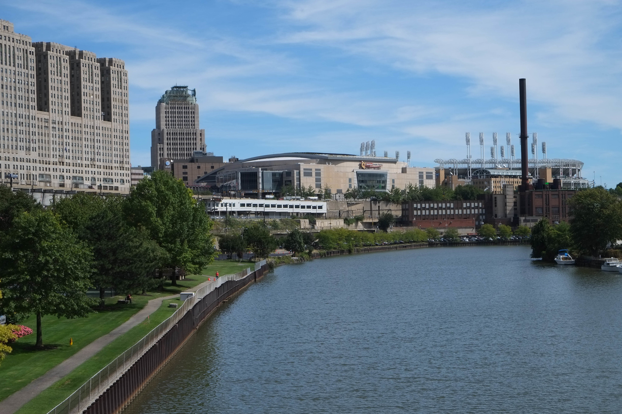 Under a clear blue sky, a river fills the foreground and a city skyline fills the background.