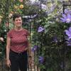 Jan Mooney stands beside purple clematis and yellow rose vines at Upper Fells Point Community Garden. (Photo courtesy of Jan Mooney.)
