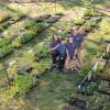 A family of 4 smile surrounded by potted native plant seedlings