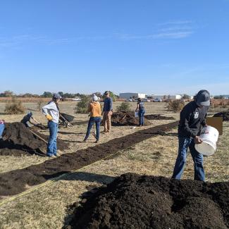 Volunteers apply cardboard, compost, and mulch to the ground to prepare for habitat restoration at a vineyard